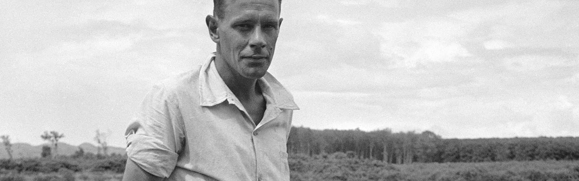 Cas Oorthuys (1908-1975), Bewapende Nederlandse rubberplanter poseert voor een pompinstallatie langs een rivier, Indonesië, 1947