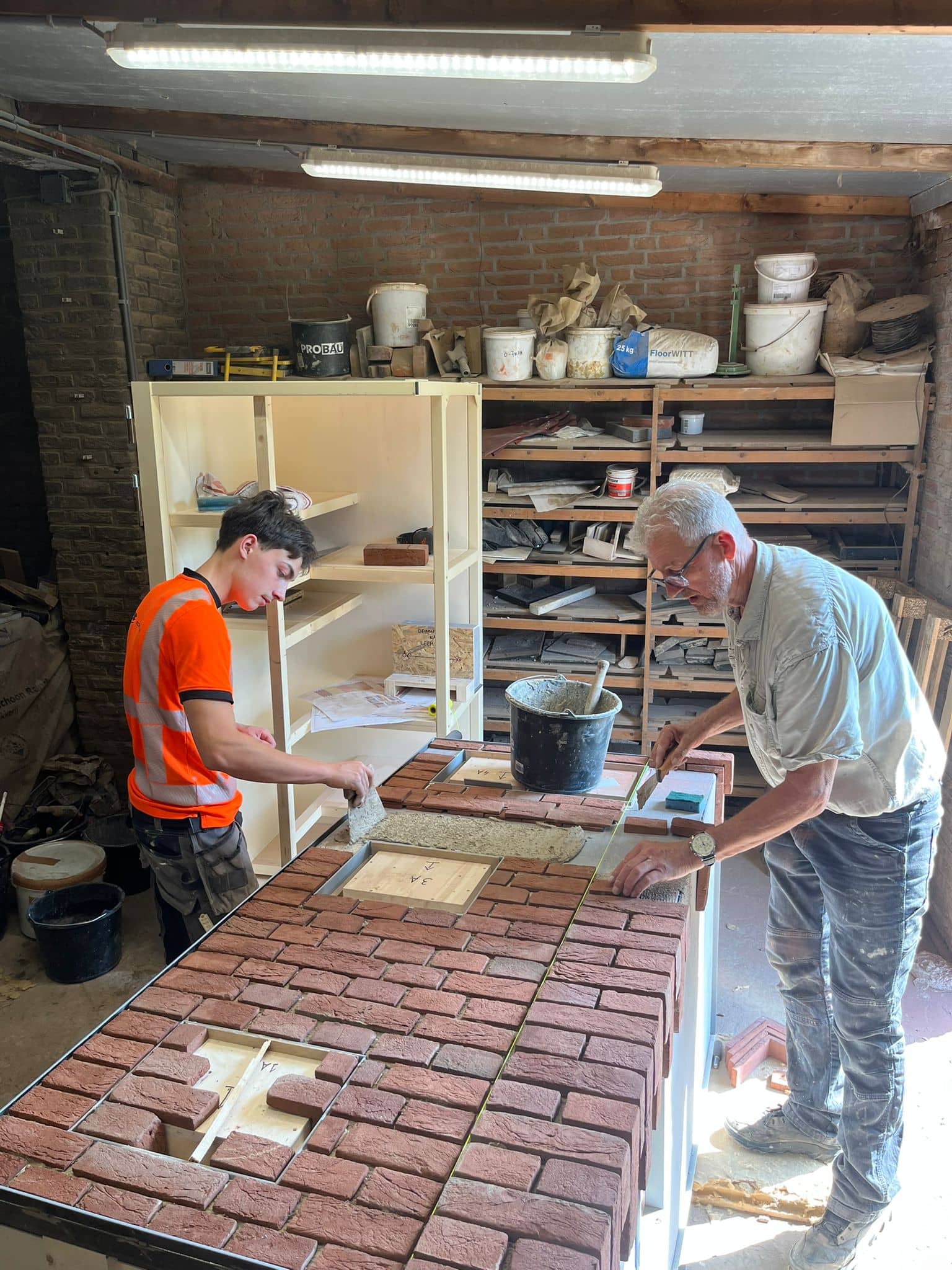 Twee personen werken aan kastwand met verschillende steensoorten en metselverbanden