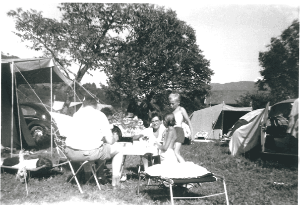 Een jong gezin zit bij een tent en eet gezamenlijk