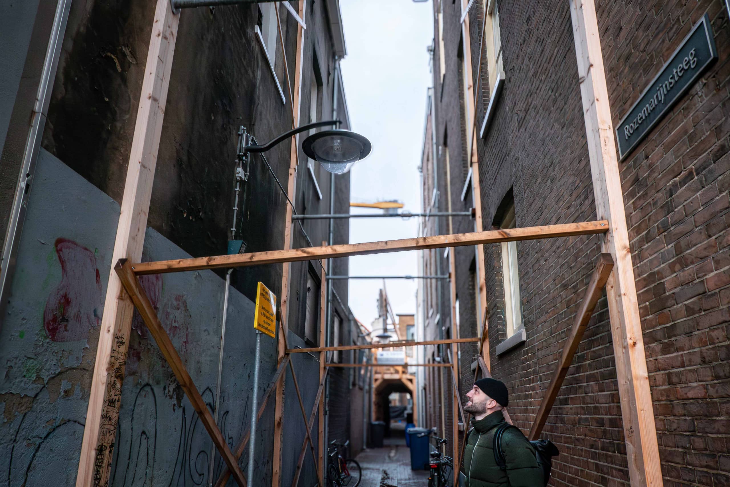 Steeg met stutwerk van planken en stalen buizen tussen gebouwen en steeg
