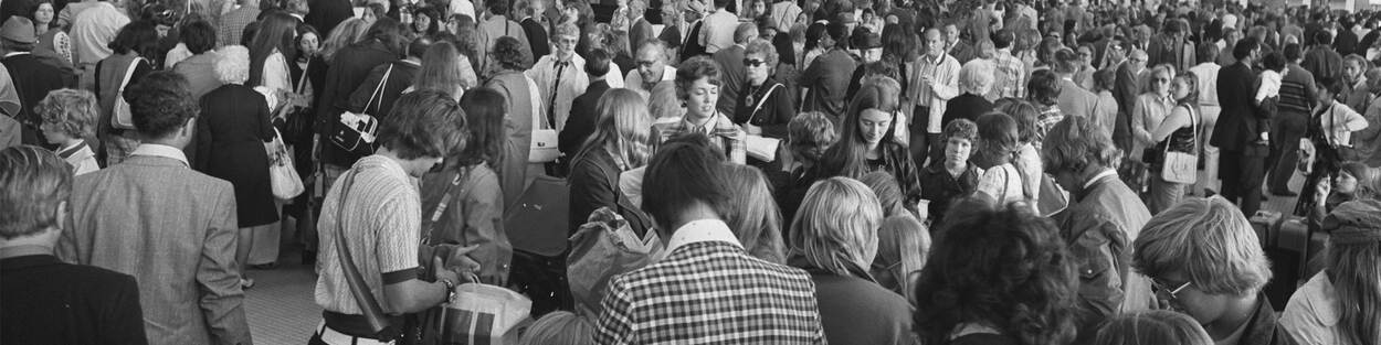 Grote groep mensen in de vertrekhal op Schiphol