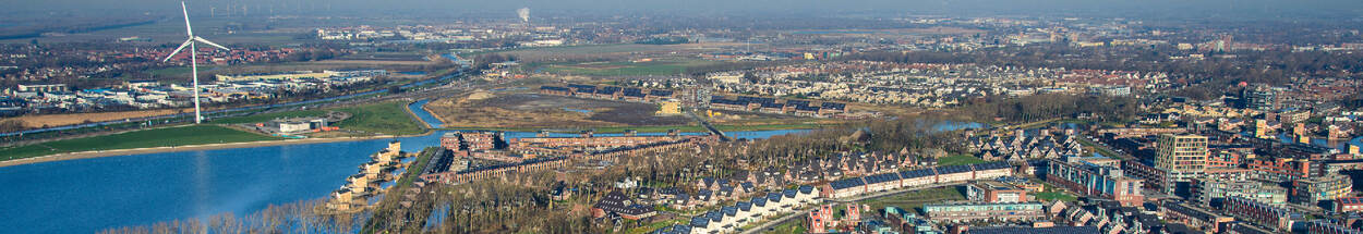 nieuwbouwwijk, water, weilanden en windmolens in de polder bij Heerhugowaard