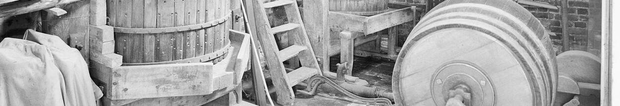 Zwartwit foto van een interieur met werktuigen en het jaartel 1866 op een balk