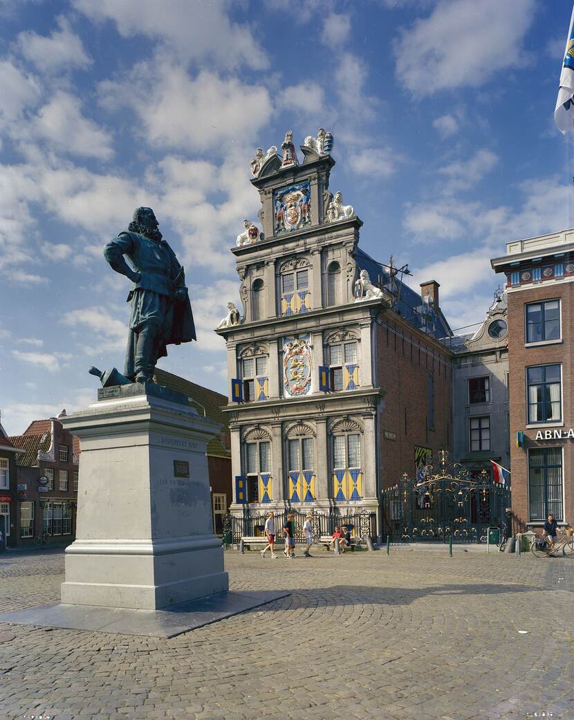 A statue on a pedestal on a square with buildings in the background