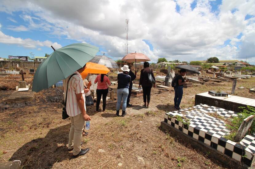 People holding umbrellas standing in between graves