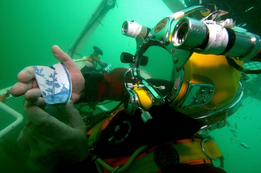 Diver holds a piece of porcelain in its hand under water