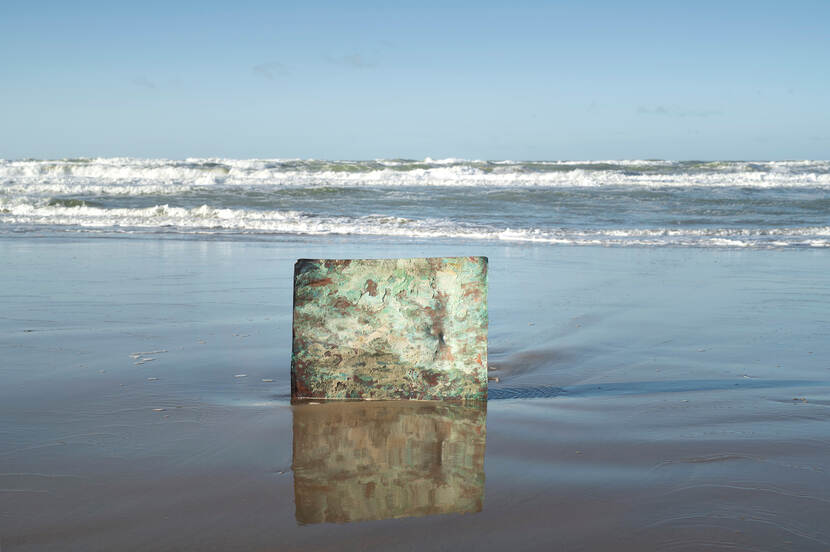 Foto van een koperplaat die uit de zee omhoog steekt