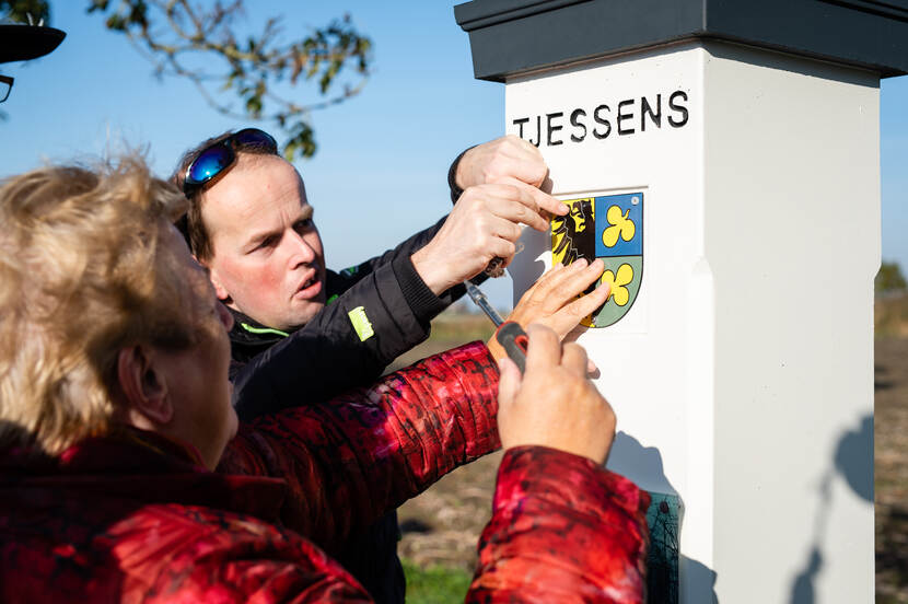 Wethouder Pytsje de Graaf van de gemeente Noardeast-Fryslân bevestigt het bordje op een van de hekpalen bij de State Tjessens. 