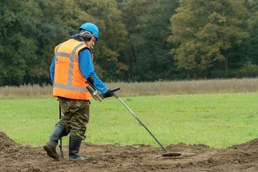 Foto van een archeoloog met een metaaldetector