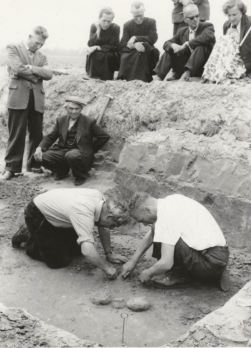 Zwartwit foto met daarop studenten, geestelijken, arbeiders en collega’s die toekijken hoe door prof. dr. Modderman (rechts) graf 96 wordt opgegraven