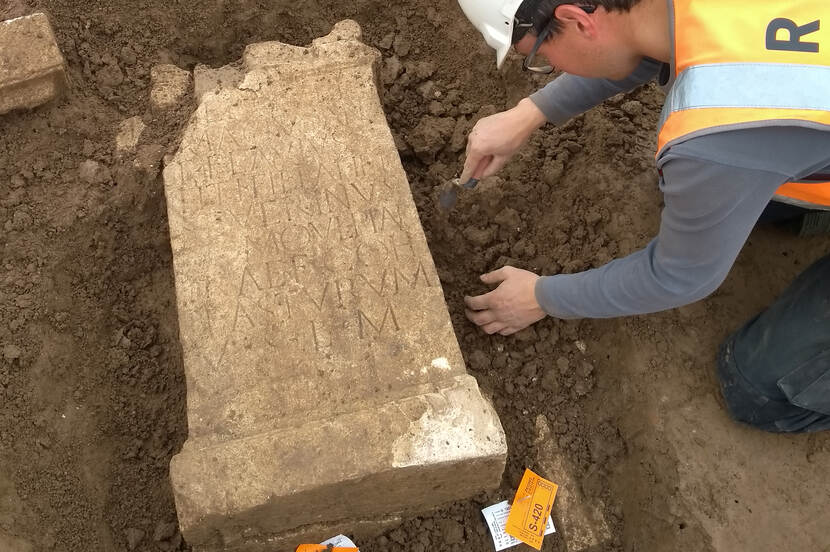 Foto van het blootleggen van een altaarsteen door een archeoloog