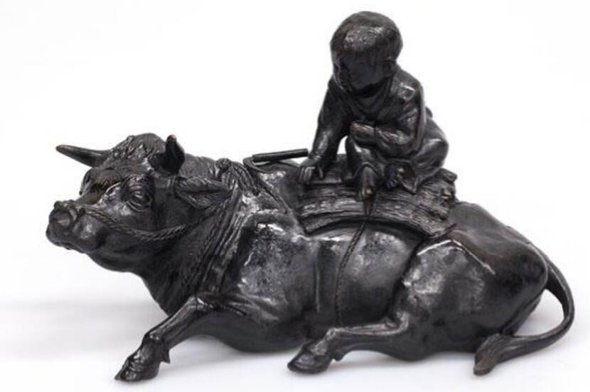 klein sculptuur van een karbouw met jongetje op de rug
