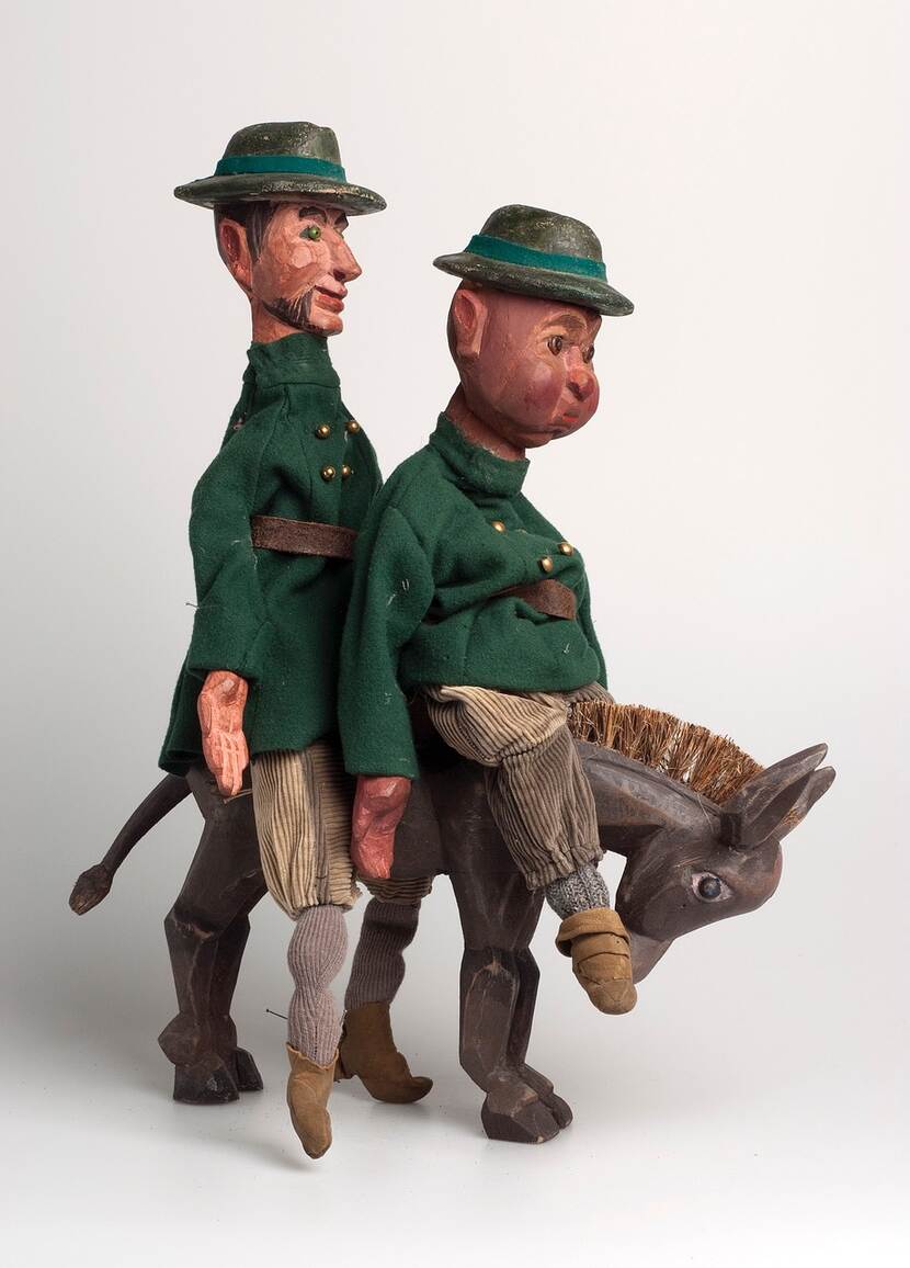 Twee poppen, voorstellende Tijl Uilenspiegel en Lamme Goedzak, achter elkaar zittend op een ezel