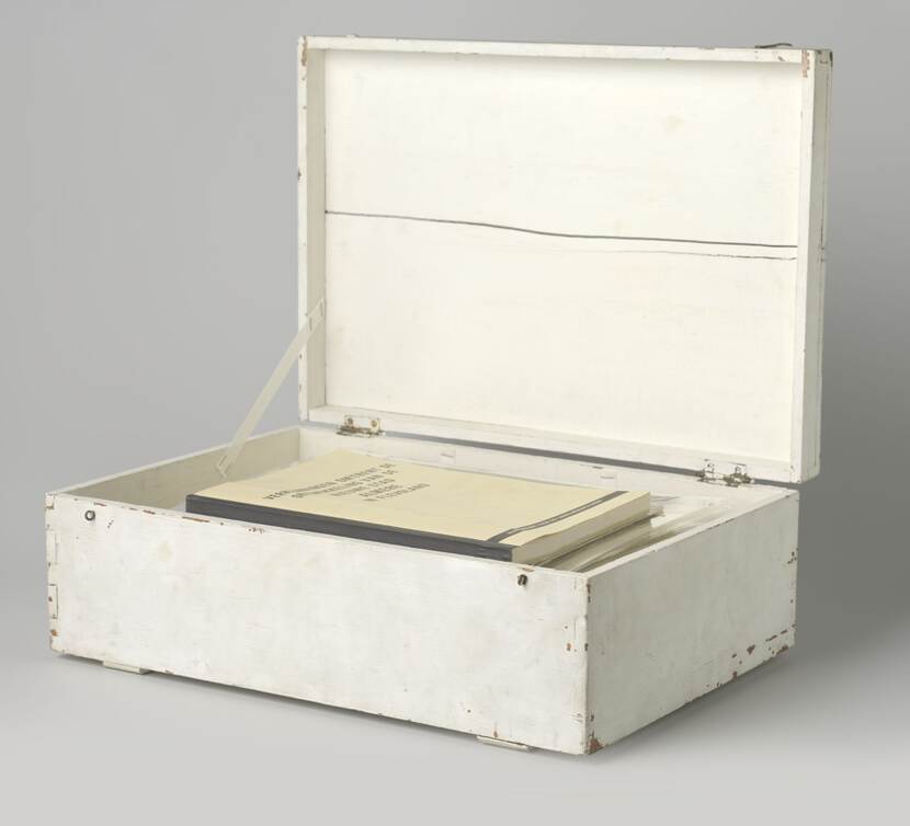 Een houten kist met de deksel open. In de kist liggen boeken.