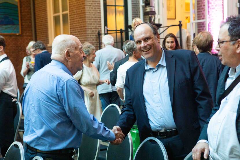 Foto van twee mannen die elkaar lachend de hand schudden