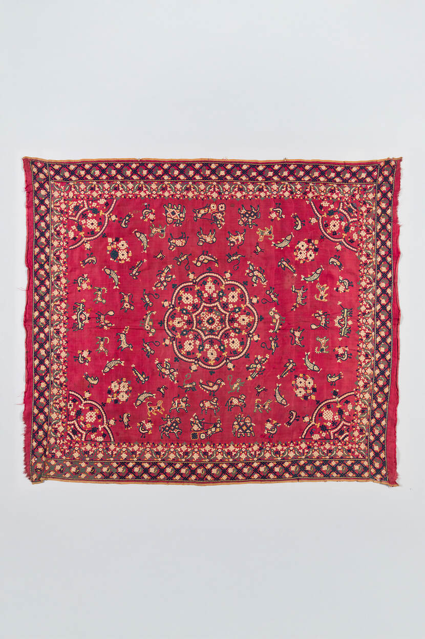 Een vierkant rood kleedje met een patroon in geel- en zwart tinten.