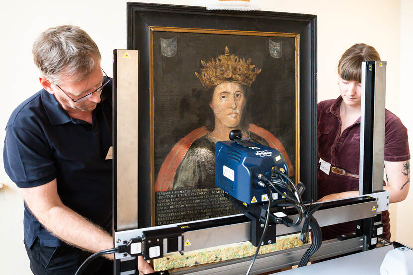 Foto van twee onderzoekers met schilderij en een XRF-scanner