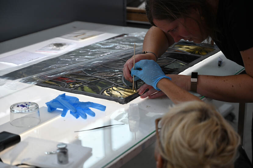 Restaurator werkt aan een glazen paneel