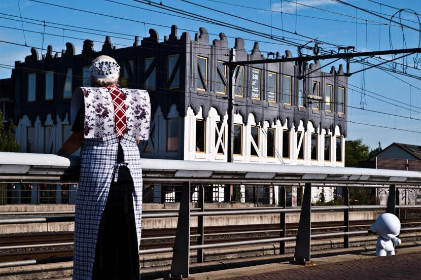 Vrouw met klederdracht voor modern gebouw in Amersfoort