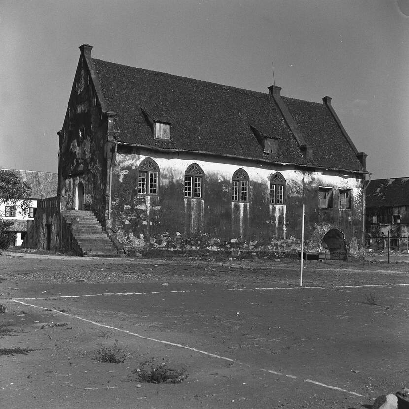 Zwartwit foto van het kerkgebouw bij Fort Rotterdam, Makassar, Indonesië met ervoor een leeg veld met witte lijn erom
