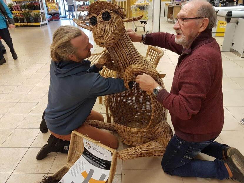 Leermeester en leerling repareren een rotan object.