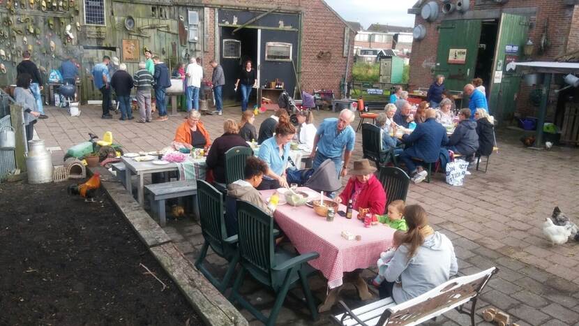 Buurtgenoten komen samen voor een barbecue bij de Fronik Boerderij