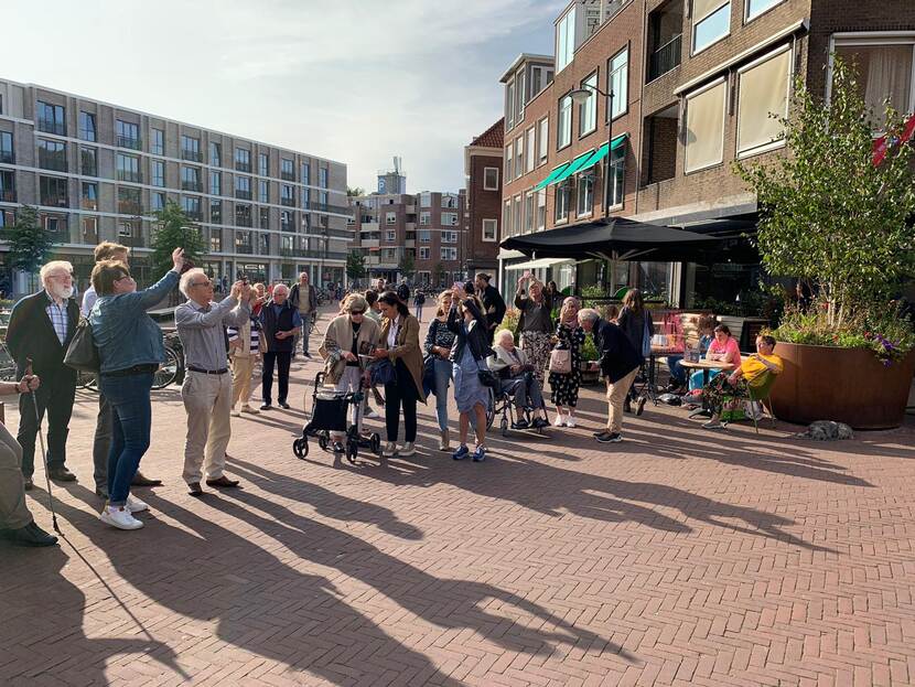 Bezoekers van de virtual reality expositie 'Vertel me alles' kijken via hun mobile telefoon naar de foto’s die in de lucht verschijnen.