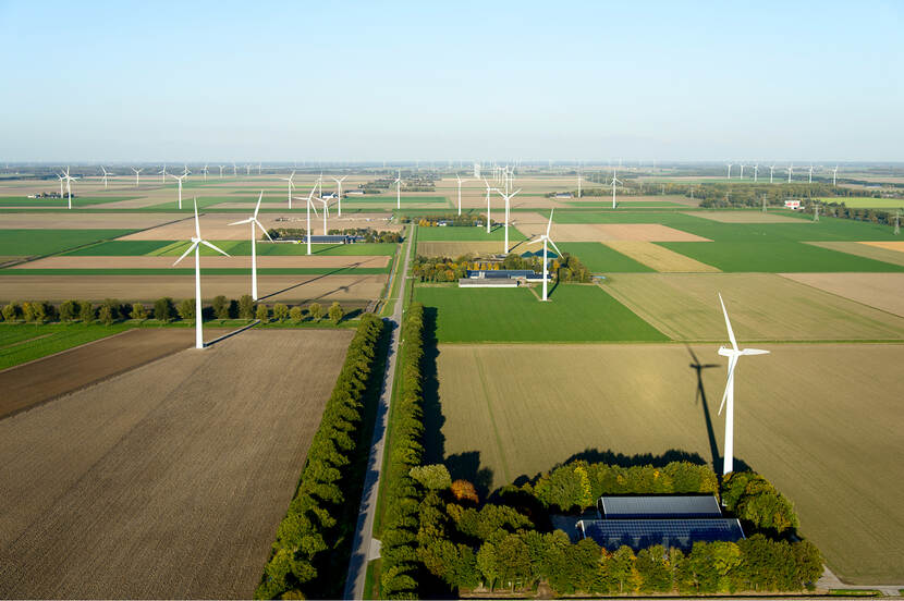 Boerderij met zonnepanelen omgeven door windmolens van een windmolenpark in Zeewolde.