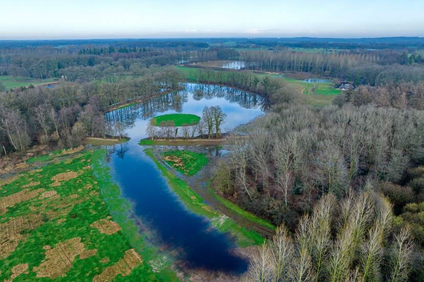 Luchtfoto van Landgoed 't Medler. Te zien is een landschap met velden, een slingerende beek en bomenrijen tot aan de horizon.