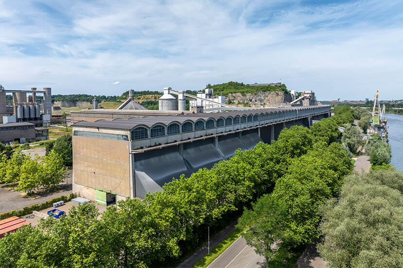 Foto van een heel langgerekt industrieel fabrieksgebouw met bomen eromheen