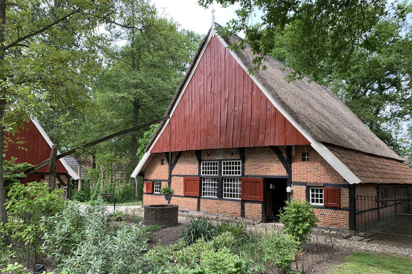 Zicht op een boerderij met daarvoor een waterput op Erve Kots.