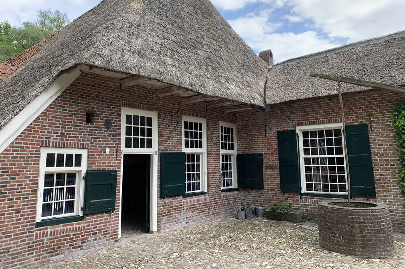 Zicht op een boerderij met daarvoor een waterput op Erve Kots.