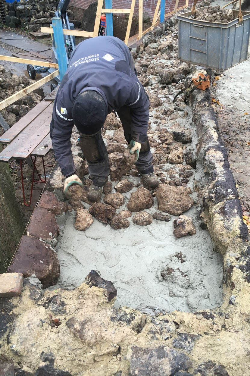 Laatste deel van het proces: de binnenkern van de muur wordt gevuld met rest ijzeroermateriaal in de metselmortel.