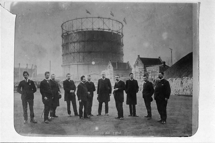 Gezelschap mannen met op de achtergrond de gashouder van de Westergasfabriek