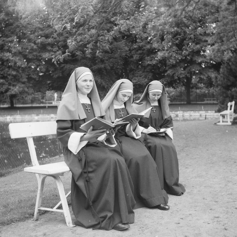 Foto van drie Zusters Franciscanessen te Veghel, lezend op een bank