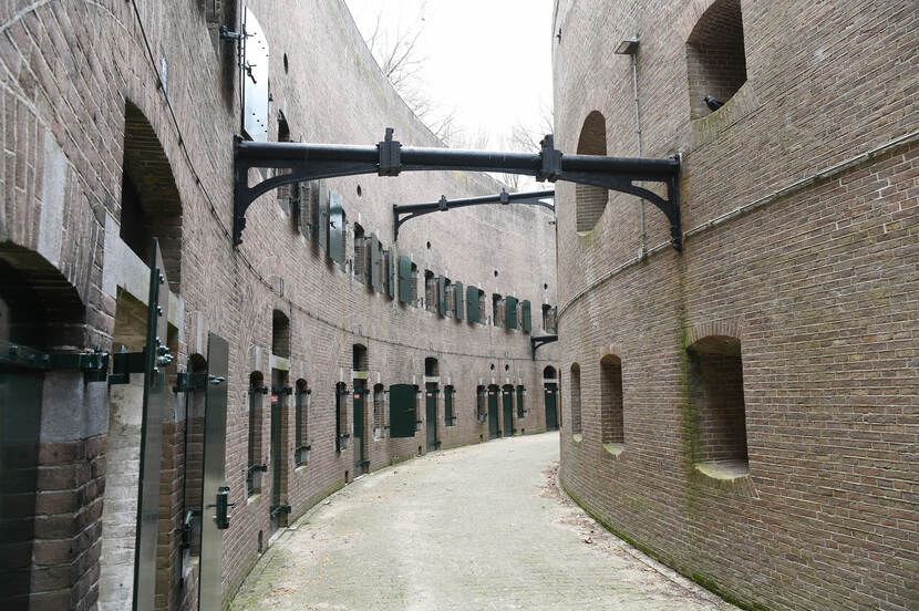 Foto van het binnenterrein van Fort Honswijk, met een loopgang tussen gebogen muren