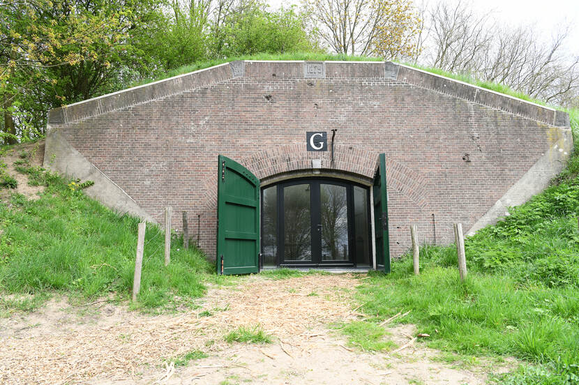 Foto van een ingewerkte gevel in Fort Honswijk met deuren en daarboven de letter G.