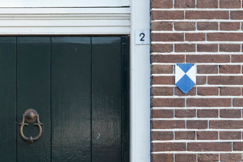 Foto van de gevel van het voormalig gemeentehuis van Havelte met detail van een deur en het blauw-witte schildje