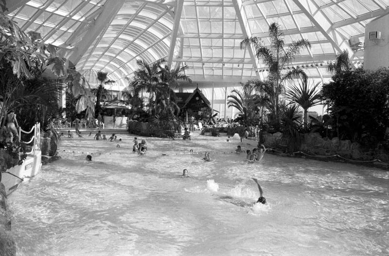Zwemmende volwassenen en kinderen in het nieuwe tropische zwembad Tropicana 1988