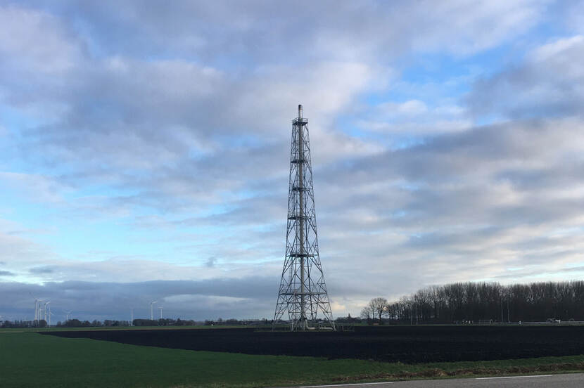 Een affakkeltoren bij de gasopslag van Tjuchem in een grasveld.