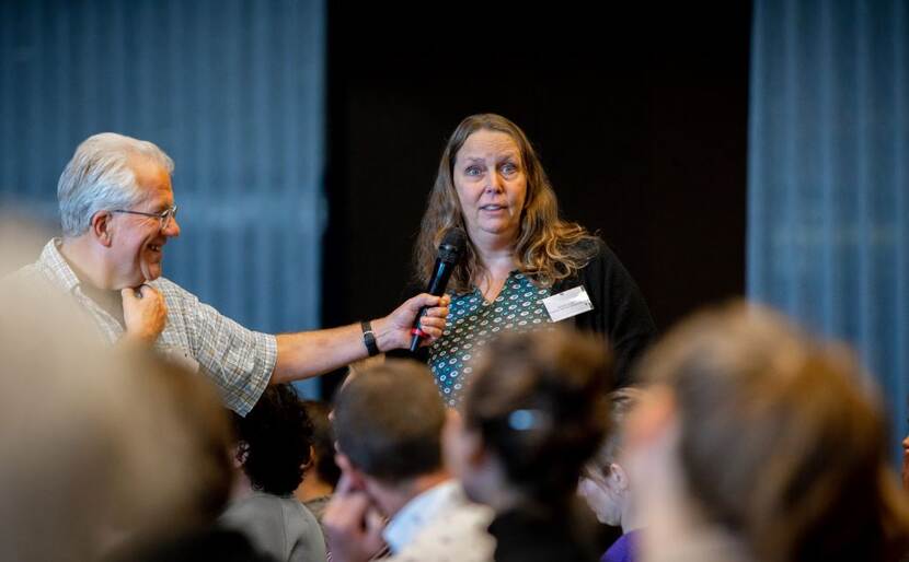 Foto van een insprekende vrouw in het publiek