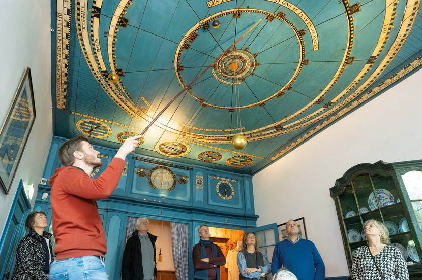 Foto van het interieur van het Eise Eisinga Planetarium uit 1781 in Franeker, met een gids die het nog werkende planetarium toelicht.