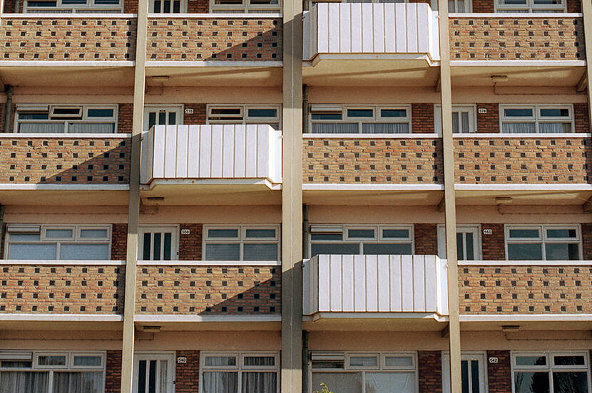 Voorgevel van de Wielewaalflat in Groningen met afwisselend geplaatste balkons en zandkleurige,opengewerkte balustrades