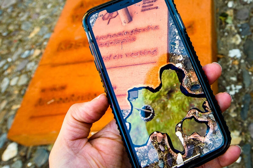 Foto van de Archeo Route App op een mobiele telefoon die in de hand wordt gehouden