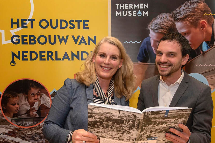 Jordy Clemens, wethouder van de gemeente Heerlen ontvangt het eerste exemplaar uit handen van Mariëtte  Pennarts-Pouw, hoofd regio Midden-Zuid, RCE