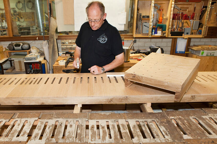 Orgelbouwer aan het werk aan een groot, houten onderdeel van het Nicolai-orgel