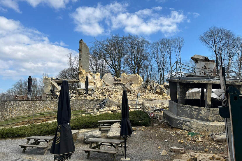 Foto van de ingestorte Wilhelminatoren met een berg puin en op de voorgrond een terras met brokstukken