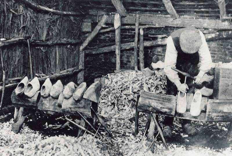Zwart-wit foto van een klompenmaker aan het werk