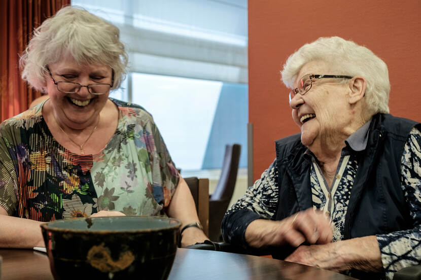 Twee dames halen lachend herinneringen op.