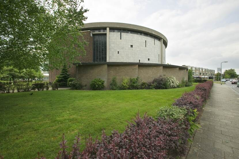 Een rond gebouw met daaromheen een groot grasveld